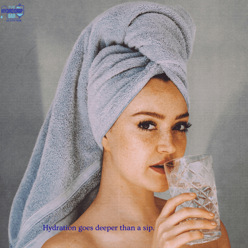 A woman with a towel wrapped around her head drinks a glass of water, highlighting the message that hydration goes deeper than a sip.