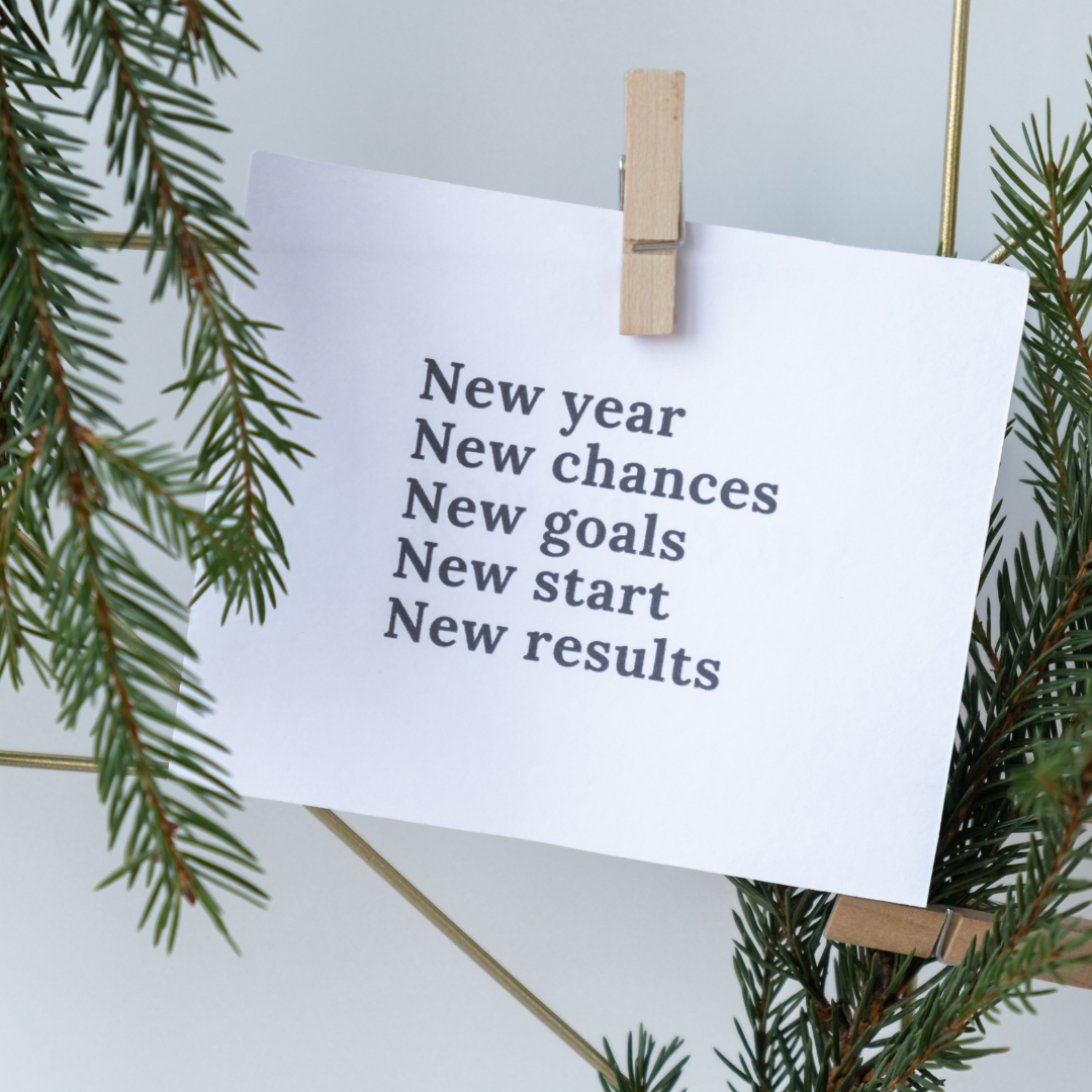 New Year wellness message reading “New year, new chances, new goals, new start, new results” clipped to a string with evergreen branches.