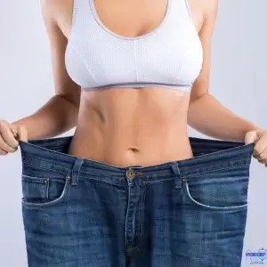 Woman showing weight loss results with oversized jeans for medical weight loss treatments at The Hydro Drip Bar